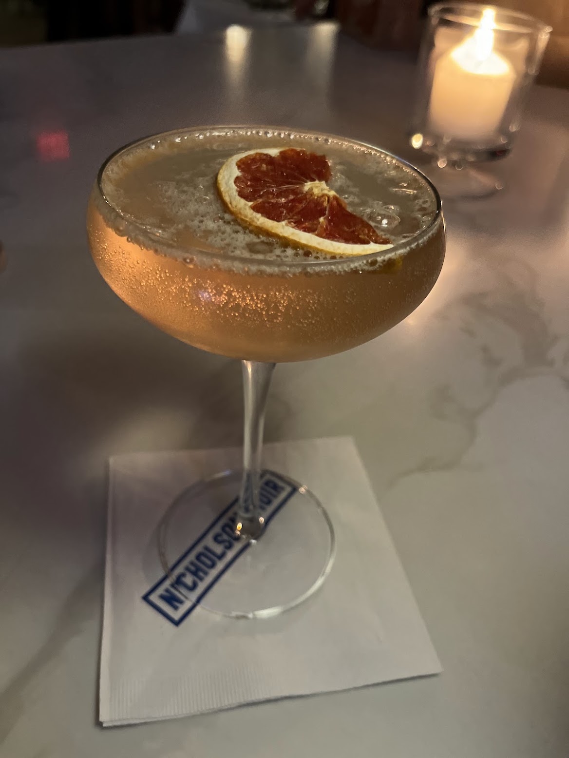 A chilled Nicholson Muir cocktail garnished with dried pink grapefruit