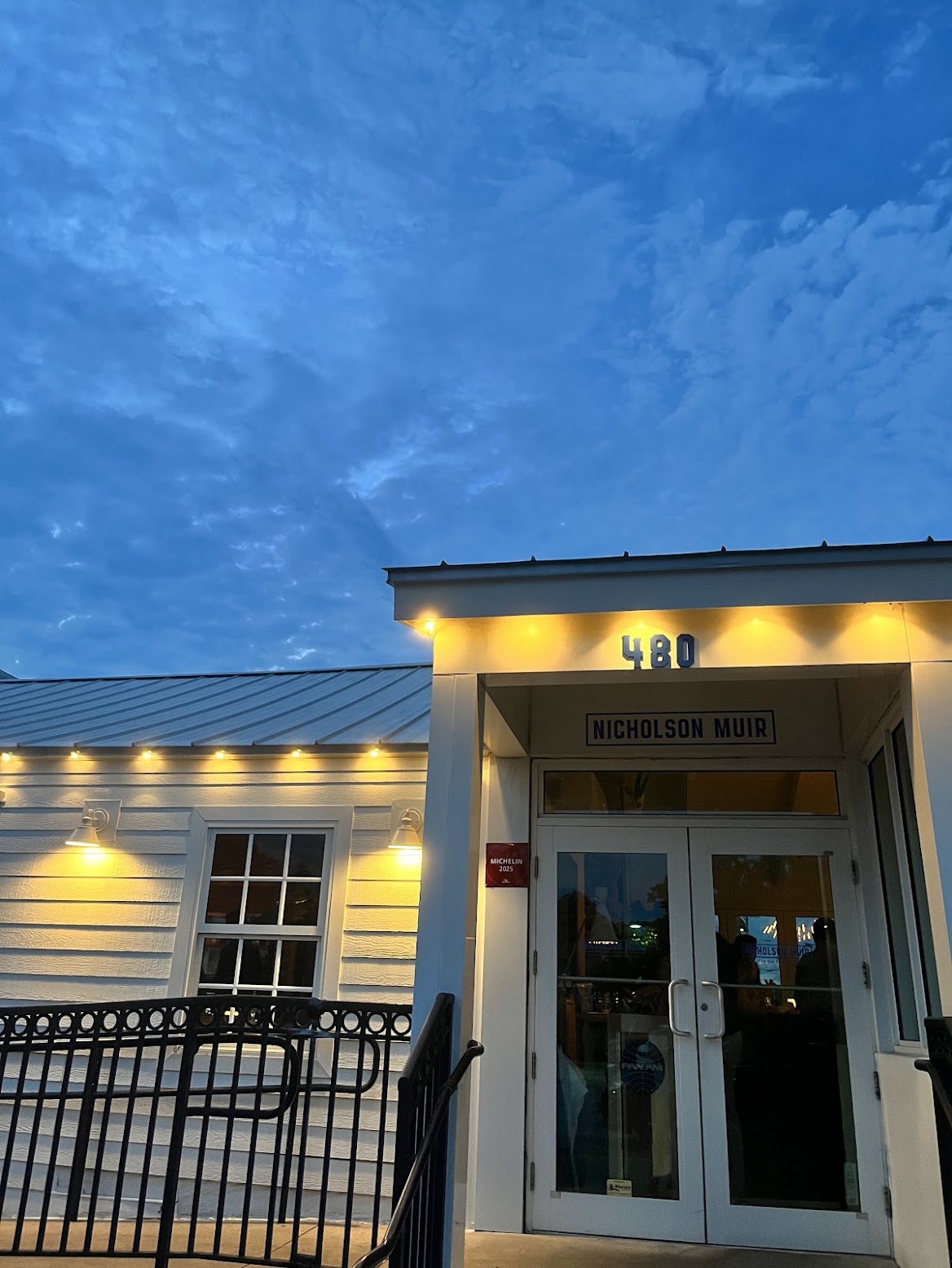 The illuminated entrance to Nicholson Muir at 480 East Ocean Avenue at dusk