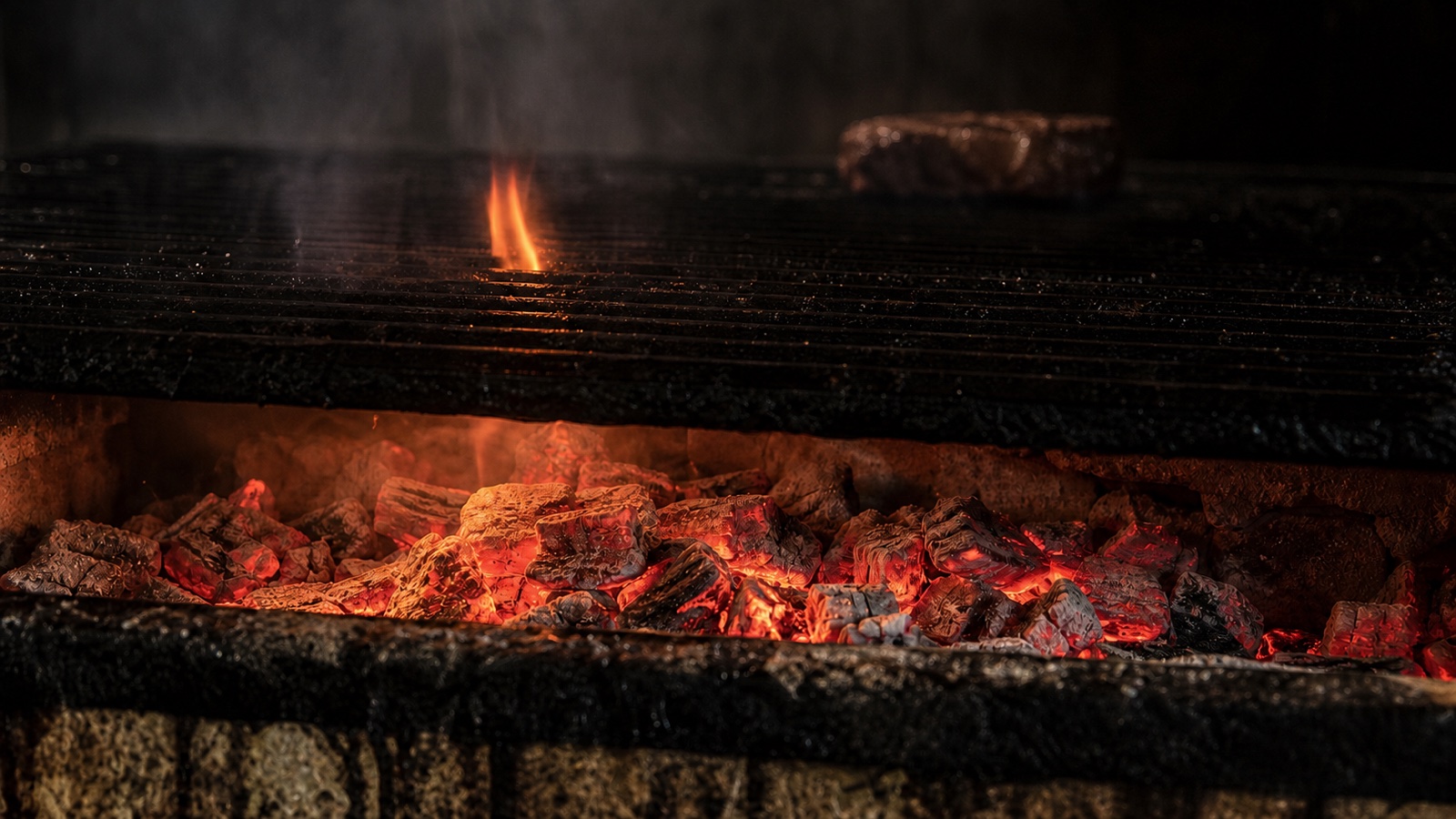 Glowing natural-charcoal embers beneath the Nicholson Muir live-fire grill